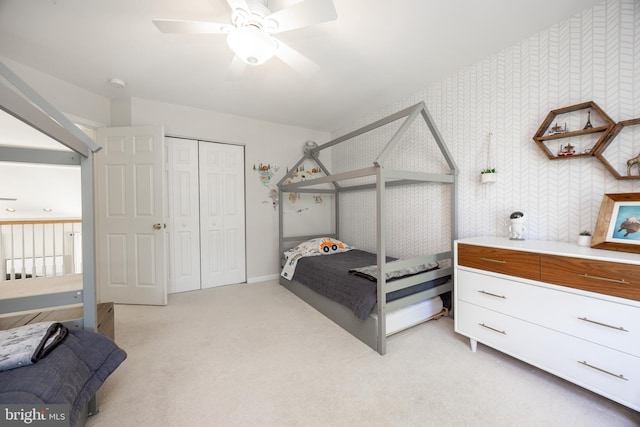bedroom with light colored carpet, a ceiling fan, baseboards, and a closet
