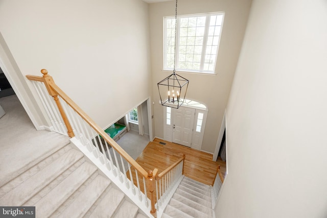 foyer featuring wood finished floors, stairway, baseboards, a notable chandelier, and a high ceiling