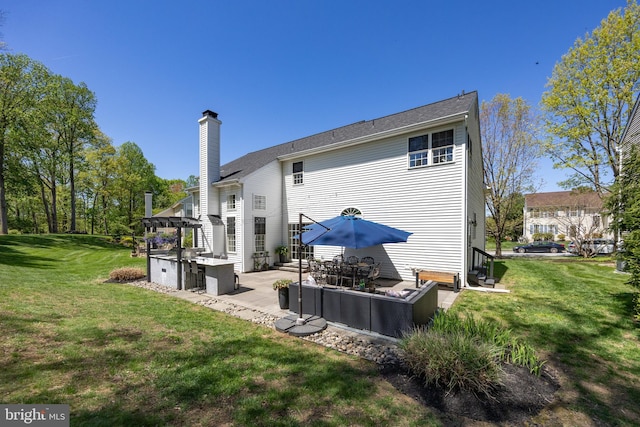 back of house featuring a patio, a chimney, and a yard