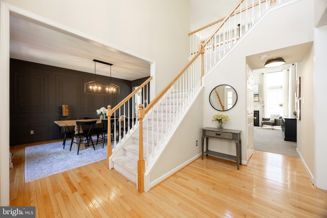 stairs featuring baseboards, a towering ceiling, and hardwood / wood-style floors