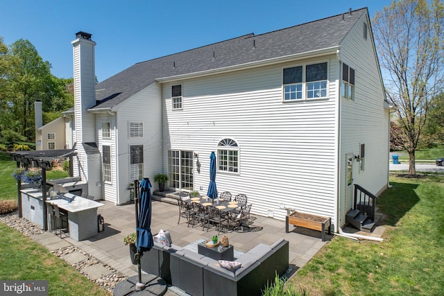 back of house with an outdoor living space, a chimney, a lawn, a patio, and entry steps