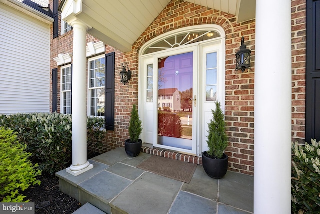 property entrance with a porch and brick siding