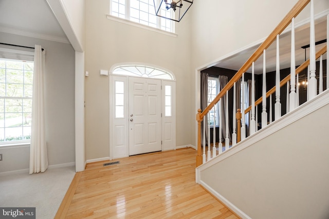 entrance foyer featuring visible vents, crown molding, stairway, and hardwood / wood-style flooring