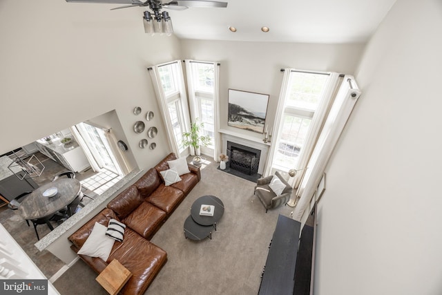 living room featuring a fireplace with flush hearth, carpet floors, ceiling fan, and vaulted ceiling