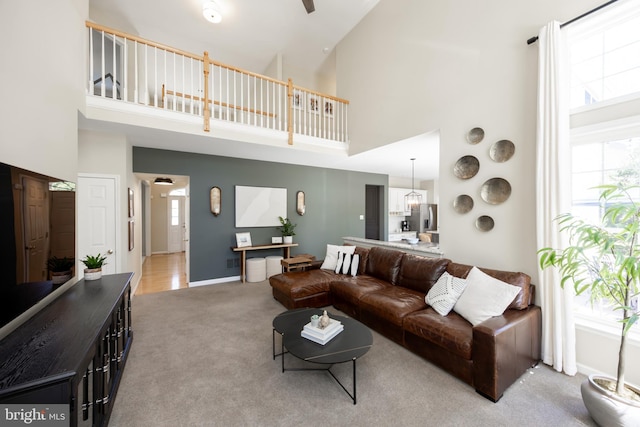 living area with baseboards, a high ceiling, and carpet