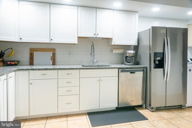 kitchen with stainless steel appliances, light tile patterned floors, white cabinetry, and a sink
