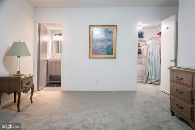 bedroom featuring connected bathroom, a spacious closet, light carpet, and a closet