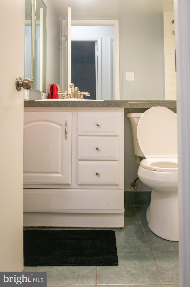 half bathroom with toilet, tile patterned floors, and vanity