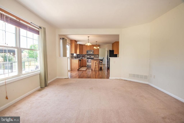134 Ascot Ct, Bear, DE 19701 - unfurnished living room featuring light colored carpet, baseboards, a chandelier, and a sink