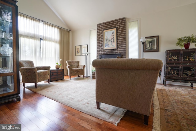 living area with high vaulted ceiling, a fireplace, and hardwood / wood-style floors