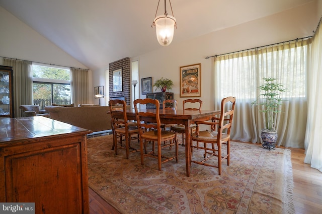 dining room with high vaulted ceiling and light wood-style floors