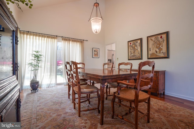 dining room featuring baseboards, a high ceiling, a chandelier, and wood finished floors