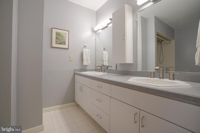 full bath featuring double vanity, tile patterned flooring, a shower, a sink, and baseboards