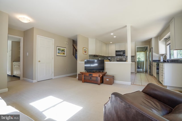 living area featuring stairway, baseboards, and light colored carpet