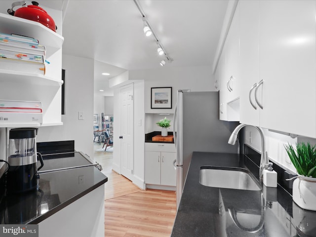 kitchen featuring open shelves, rail lighting, a sink, white cabinets, and light wood-style flooring