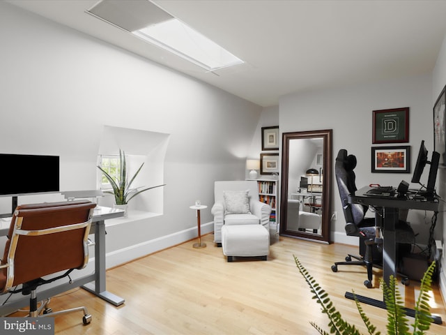 office space featuring baseboards, wood finished floors, and a skylight