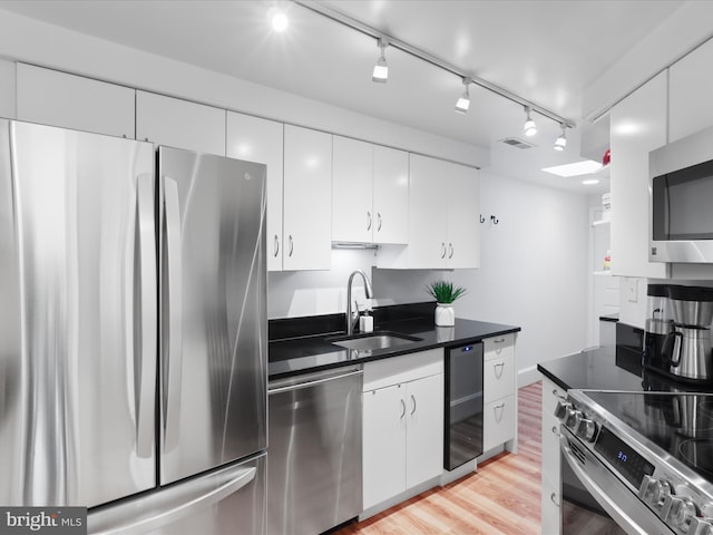 kitchen featuring visible vents, appliances with stainless steel finishes, a sink, beverage cooler, and white cabinetry
