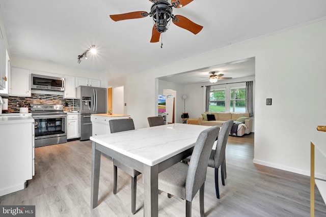 dining space with light wood-style floors, ceiling fan, and baseboards