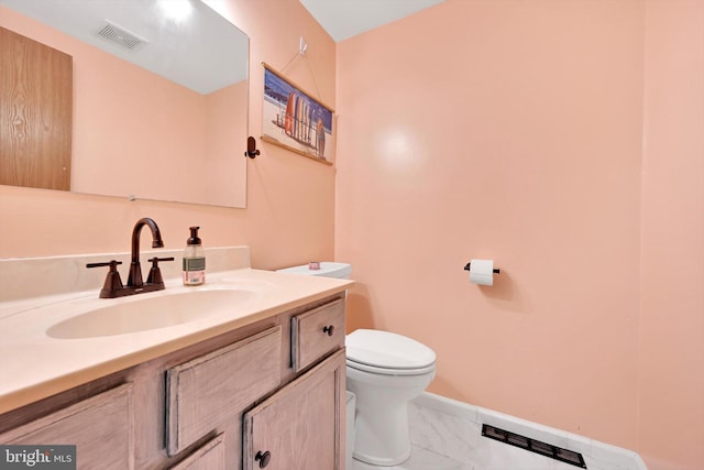 half bath featuring toilet, marble look tiles, baseboards, and vanity