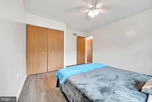 bedroom with light wood-style floors, baseboards, a closet, and ceiling fan