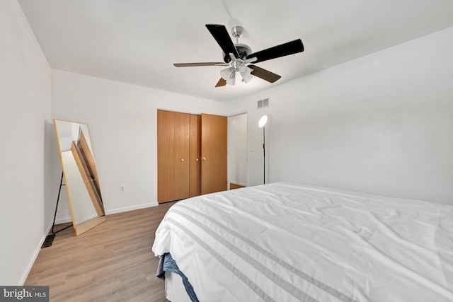 bedroom with light wood-style flooring, baseboards, ceiling fan, and a closet