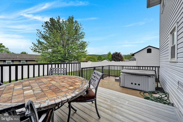 wooden terrace with a hot tub, outdoor dining area, and a fenced backyard