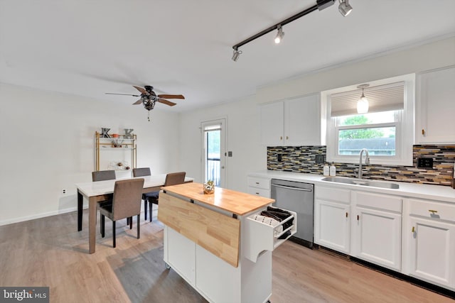 kitchen featuring a sink, stainless steel dishwasher, tasteful backsplash, wood counters, and healthy amount of natural light