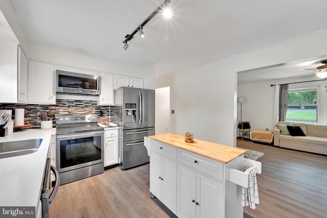 kitchen featuring appliances with stainless steel finishes, wooden counters, backsplash, white cabinetry, and ornamental molding