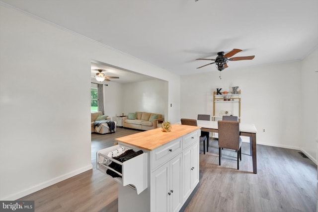 kitchen with ceiling fan, butcher block countertops, light wood-style floors, white cabinetry, and crown molding