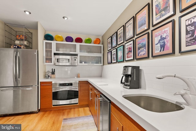 kitchen featuring brown cabinetry, light countertops, tasteful backsplash, a sink, and stainless steel appliances
