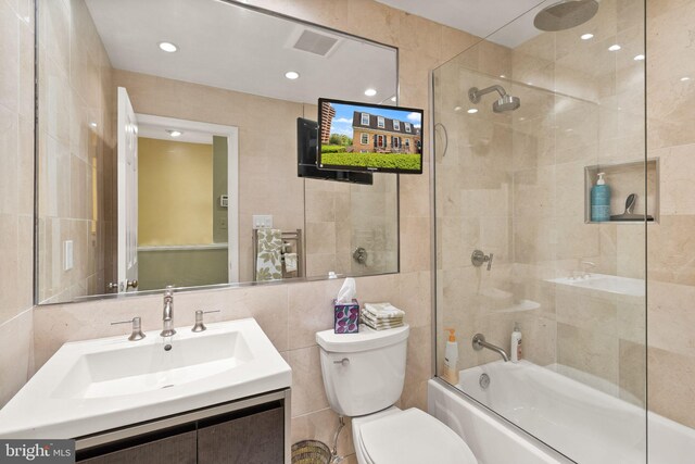 bathroom featuring vanity, visible vents, toilet, tile walls, and bath / shower combo with glass door