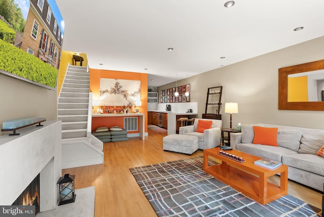 living area featuring stairs, indoor bar, and wood finished floors