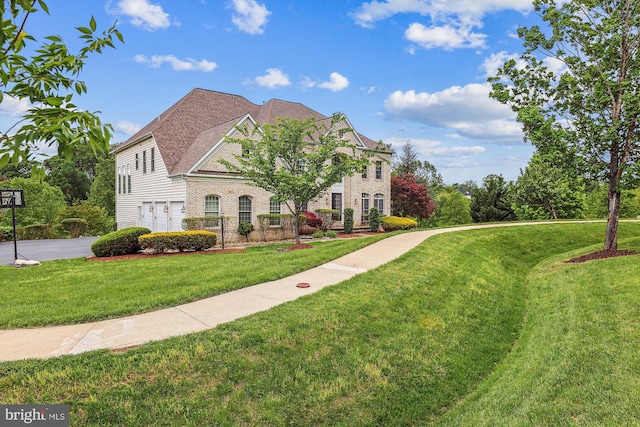 view of front of property featuring an attached garage, a front lawn, brick siding, and driveway
