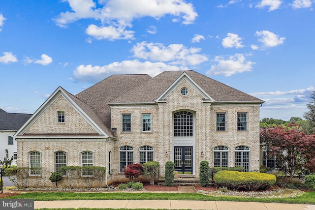 colonial-style house featuring brick siding and a shingled roof