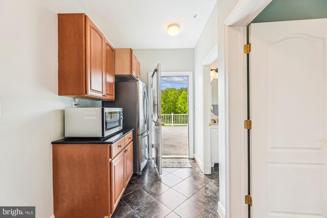 kitchen featuring appliances with stainless steel finishes, dark countertops, baseboards, and brown cabinets