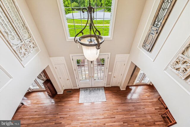 foyer with a towering ceiling, wood finished floors, baseboards, and french doors