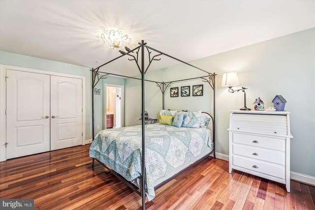 bedroom featuring a closet, wood finished floors, a chandelier, and baseboards