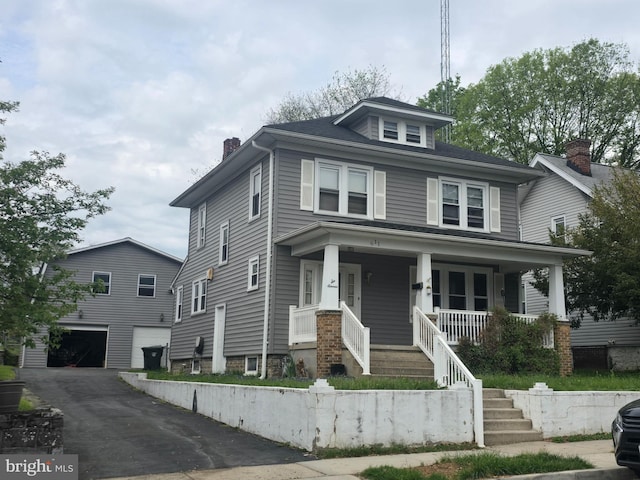 traditional style home with a garage, a chimney, a porch, driveway, and stairway