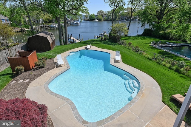 outdoor pool featuring a lawn, a diving board, fence, and a water view