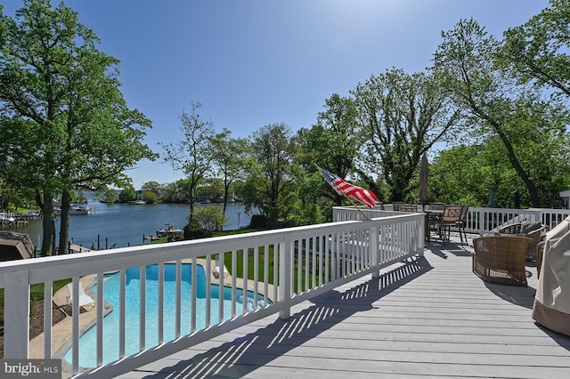 wooden terrace with outdoor dining area, a water view, and an outdoor pool