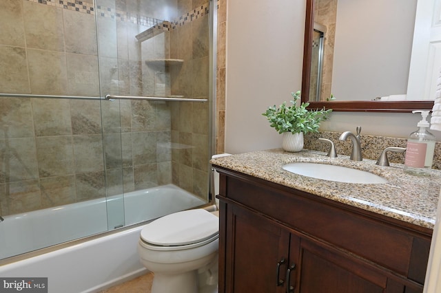 bathroom featuring toilet, shower / bath combination with glass door, and vanity