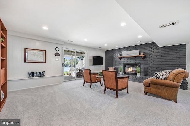 living room with a brick fireplace, recessed lighting, visible vents, and carpet