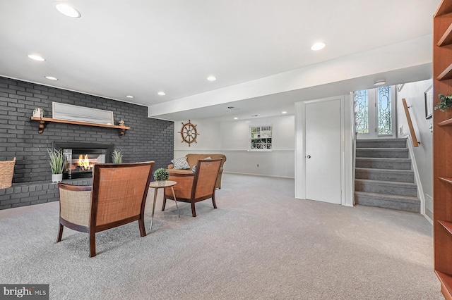 living area with stairs, a brick fireplace, brick wall, light carpet, and recessed lighting