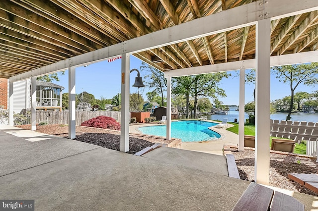 view of pool with fence, a shed, a fenced in pool, a water view, and a patio