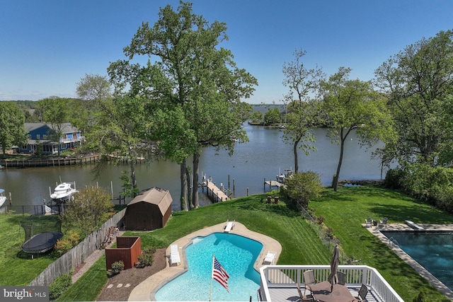 view of swimming pool with a storage shed, a fenced in pool, a diving board, and a water view
