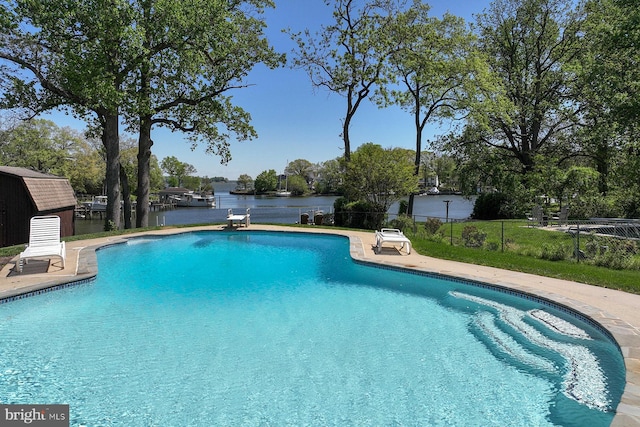 view of swimming pool featuring fence, a diving board, a fenced in pool, a water view, and a patio