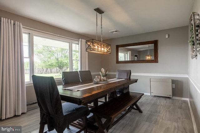 dining area featuring baseboards, a wealth of natural light, an inviting chandelier, and light wood-type flooring