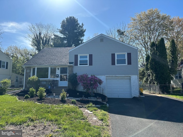 tri-level home with a garage, fence, and driveway