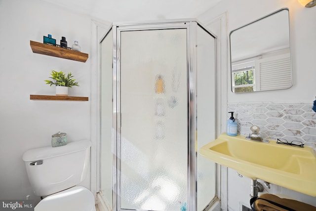 bathroom with a sink, decorative backsplash, a shower stall, and toilet