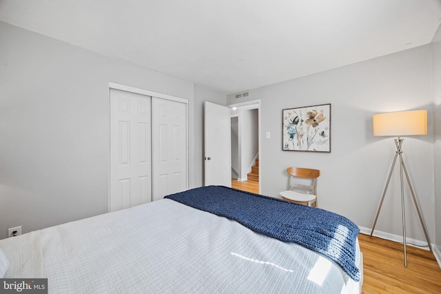 bedroom featuring visible vents, baseboards, wood finished floors, and a closet